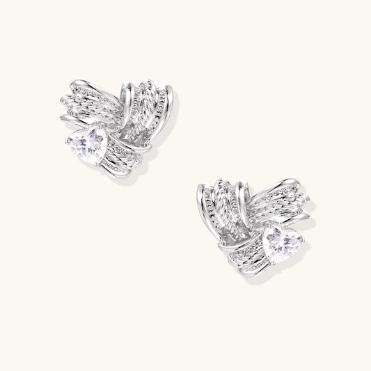 Gold-plated brass stud earrings with intricate twisted knot design and sparkling zirconia stones on neutral background.