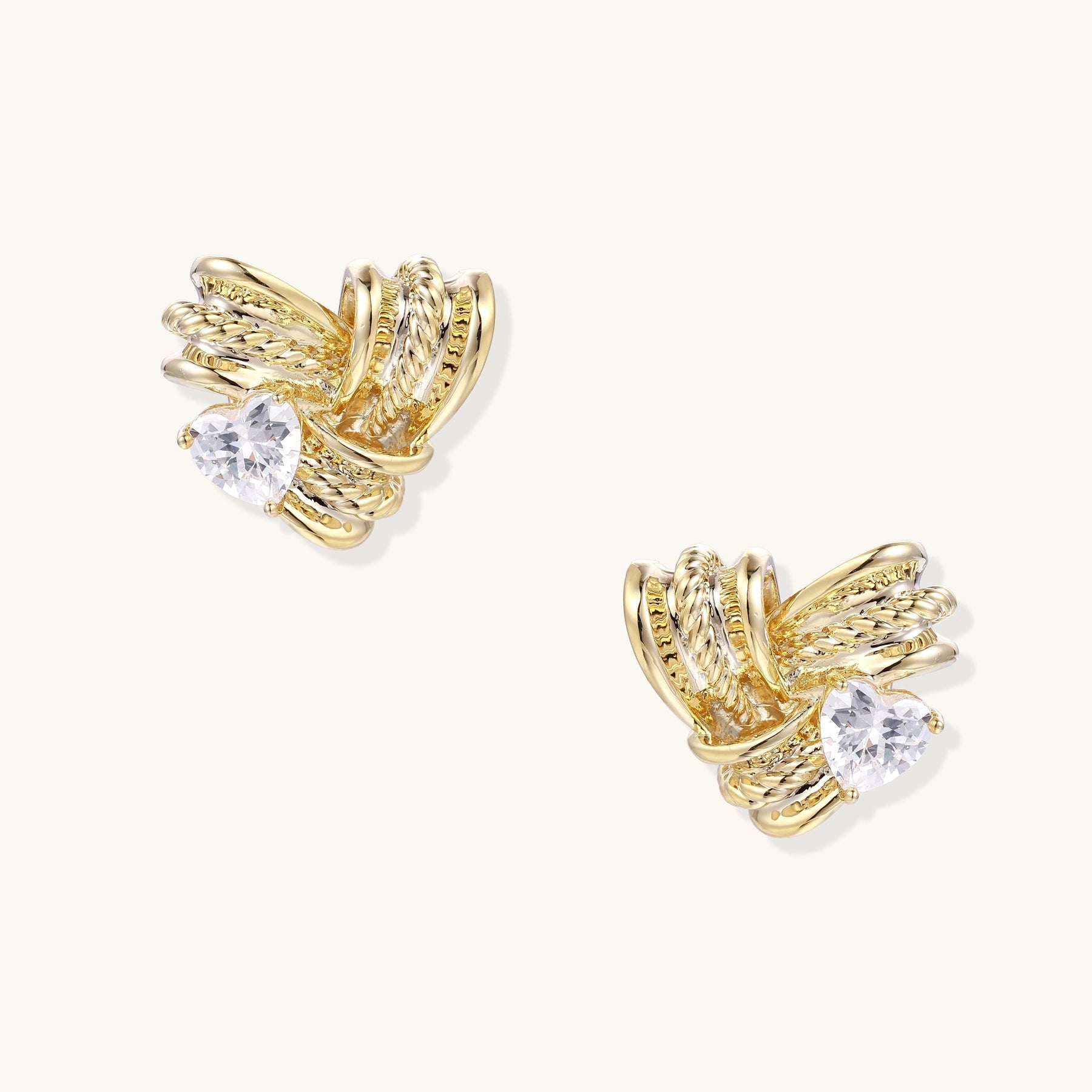 Close-up of gold-plated twisted rope design stud earrings with clear zirconia crystals on white background.