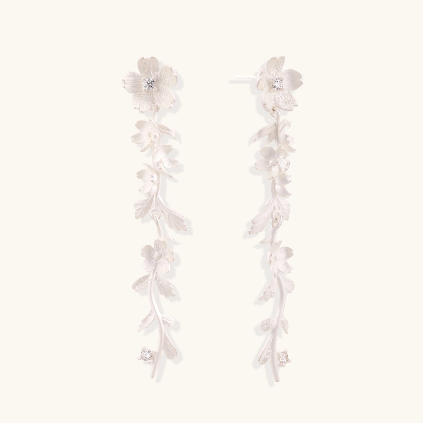 Pair of sterling silver dangle earrings with intricate leaf vine patterns and crystal accents on white background.