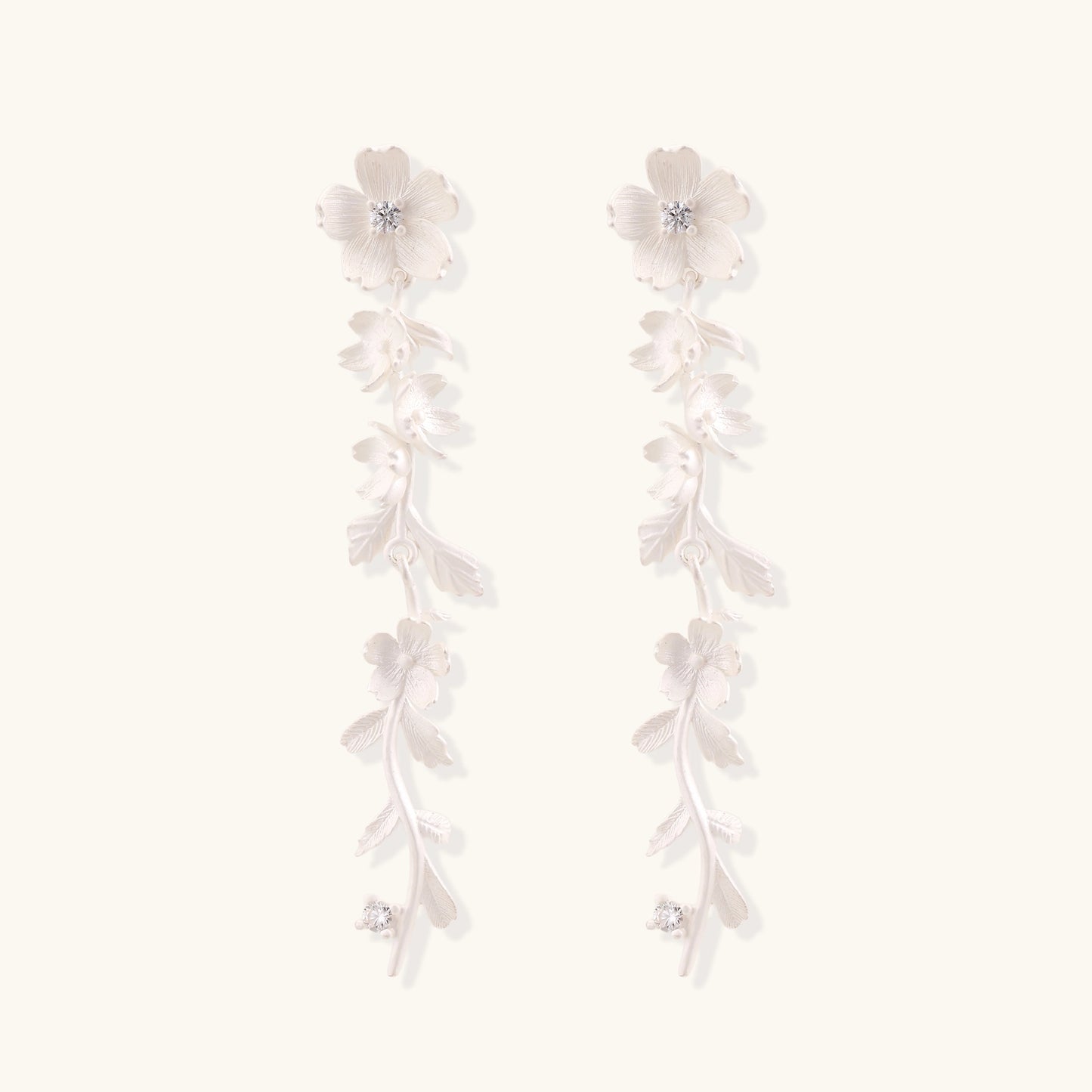 Pair of sterling silver dangle earrings with intricate leaf vine patterns and crystal accents on white background.