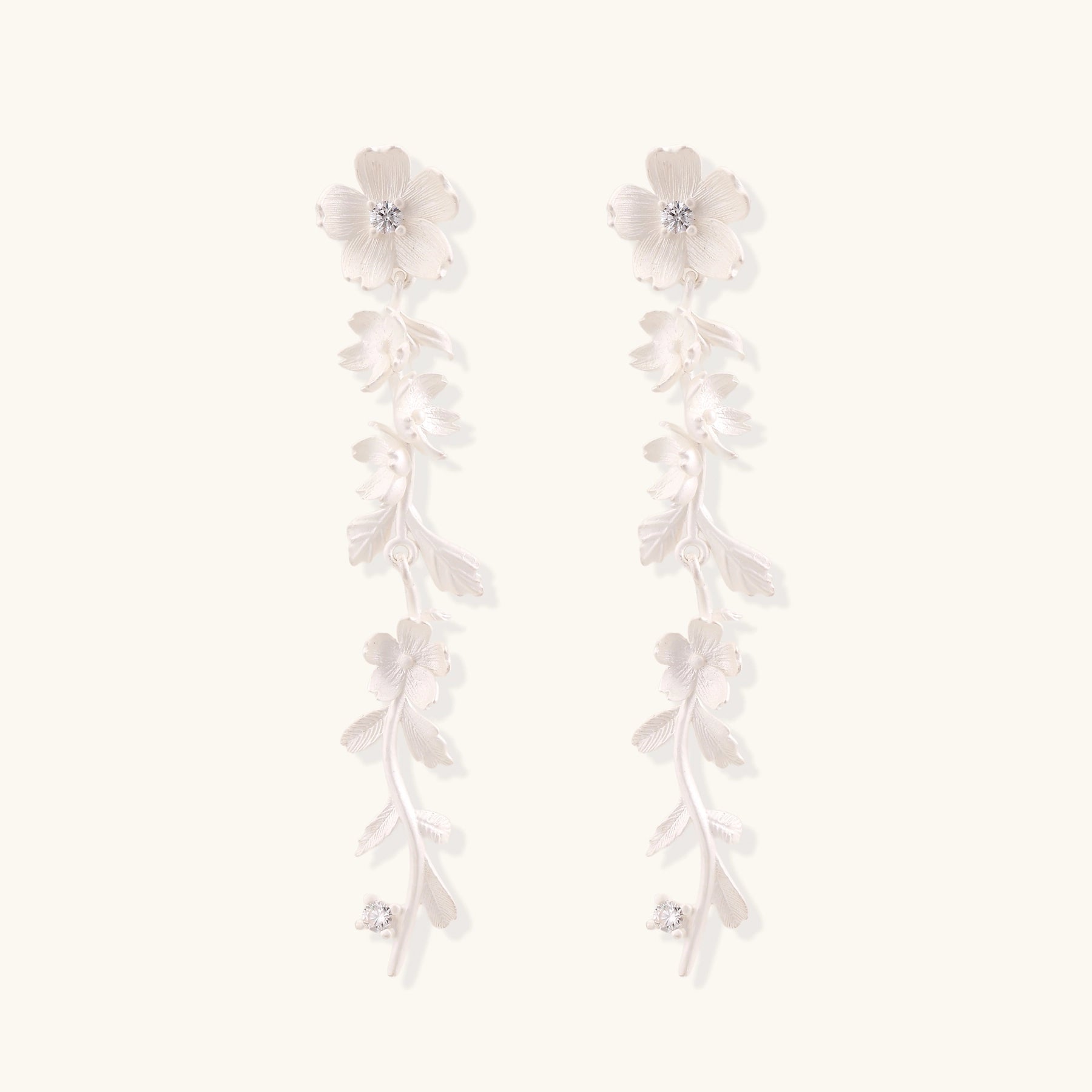 Pair of sterling silver dangle earrings with intricate leaf vine patterns and crystal accents on white background.