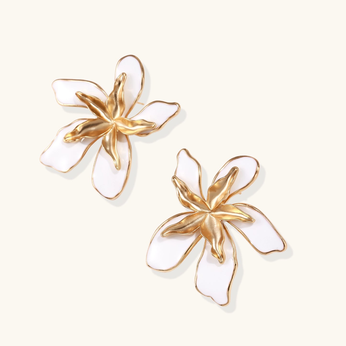 Large floral stud earrings with gold-plated brass petals and white enamel centers on neutral background