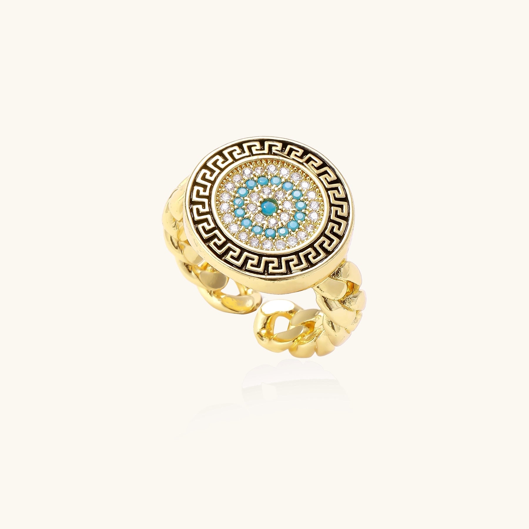 Gold-plated brass ring with Greek key border, evil eye center, and turquoise cubic zirconia stones in chunky chain band style.