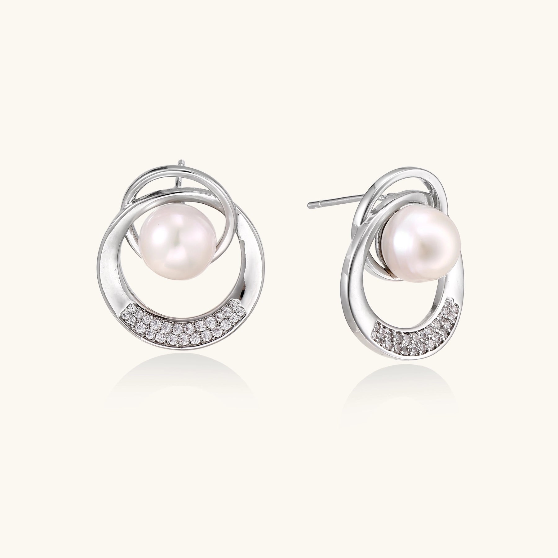 Gold-plated brass stud earrings with swirled circular design holding white freshwater pearls and small crystals