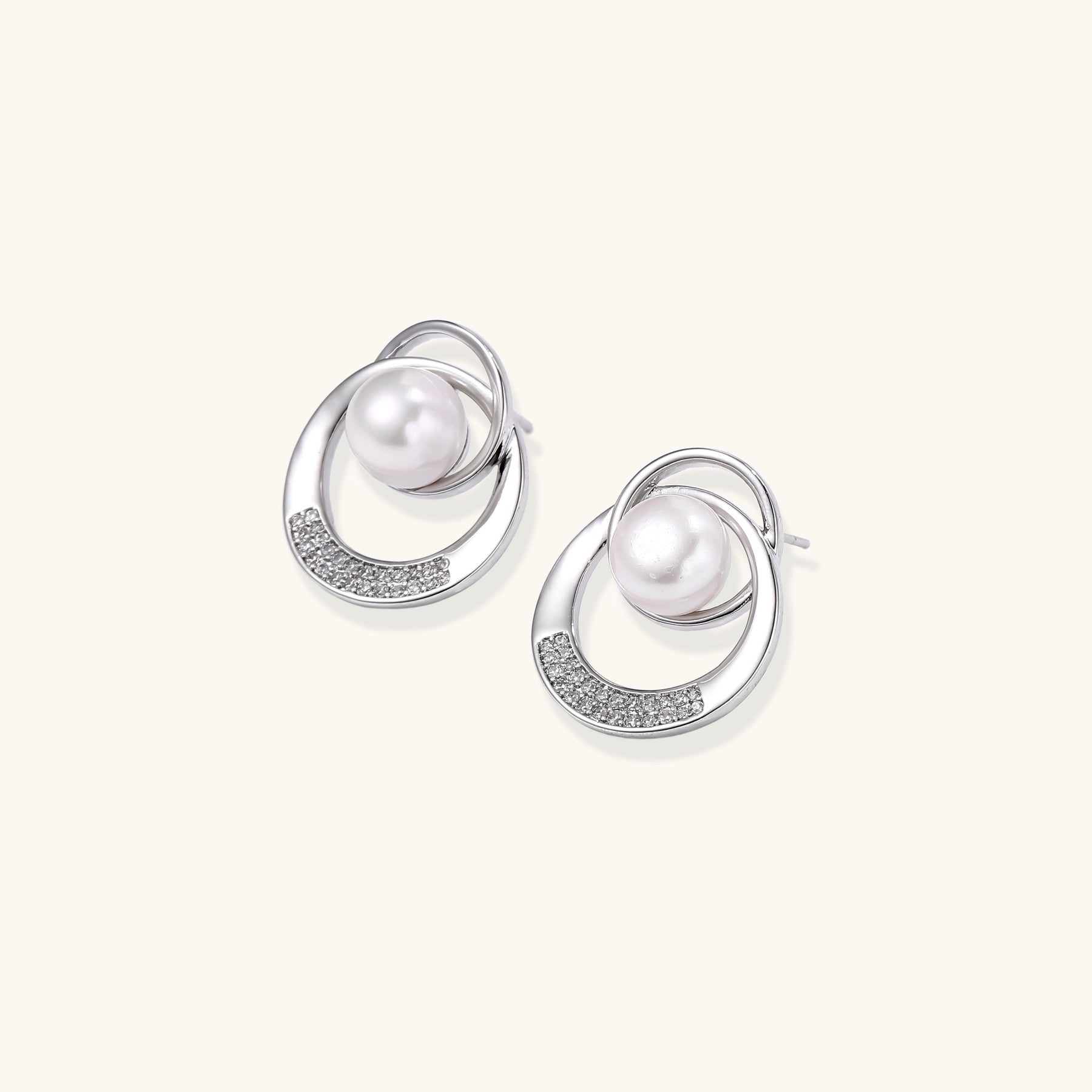 Gold-plated brass stud earrings with swirled circular design holding white freshwater pearls and small crystals