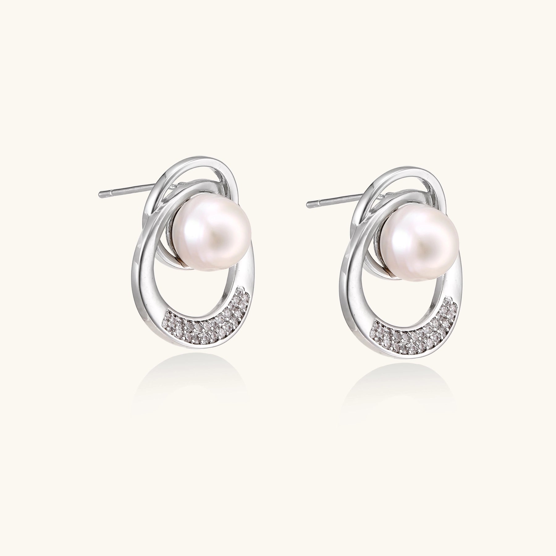 Gold-plated brass stud earrings with swirled circular design holding white freshwater pearls and small crystals