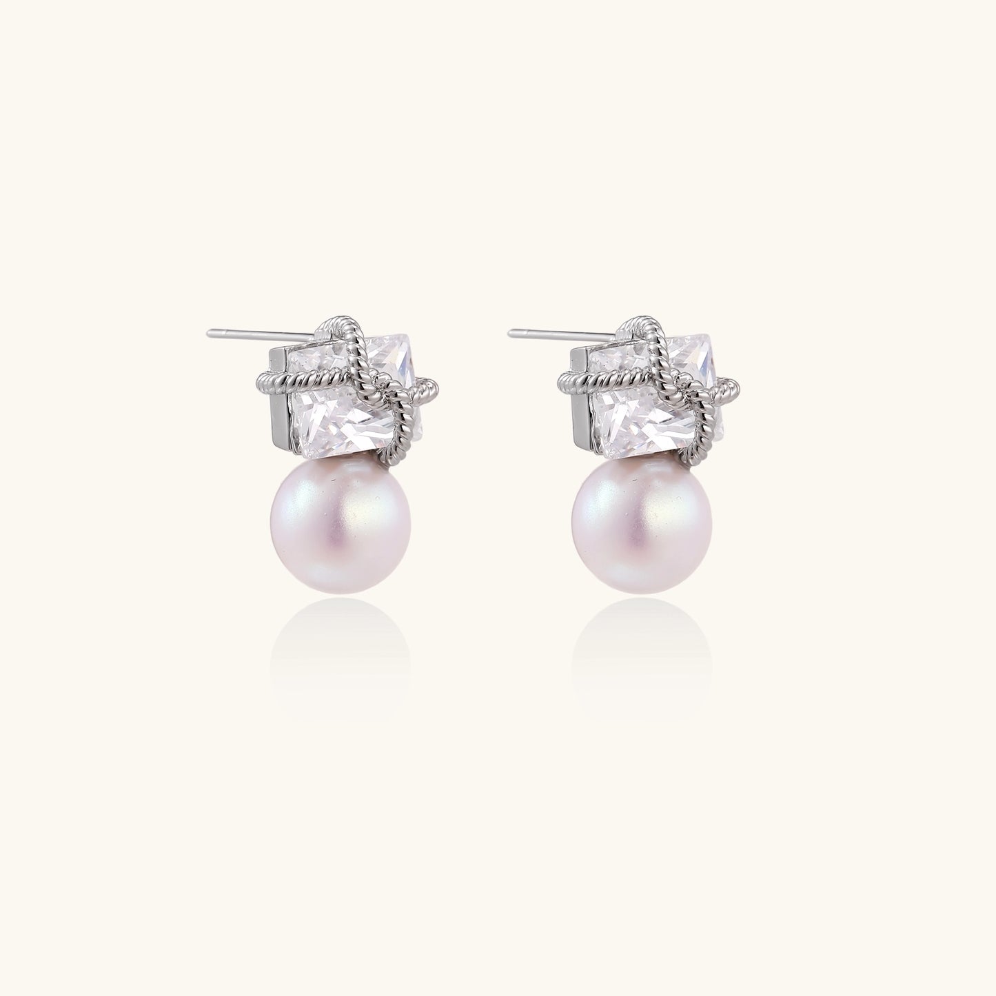 Gold-plated stud earrings with square crystal tops wrapped in twisted wire and freshwater pearl drops on white background