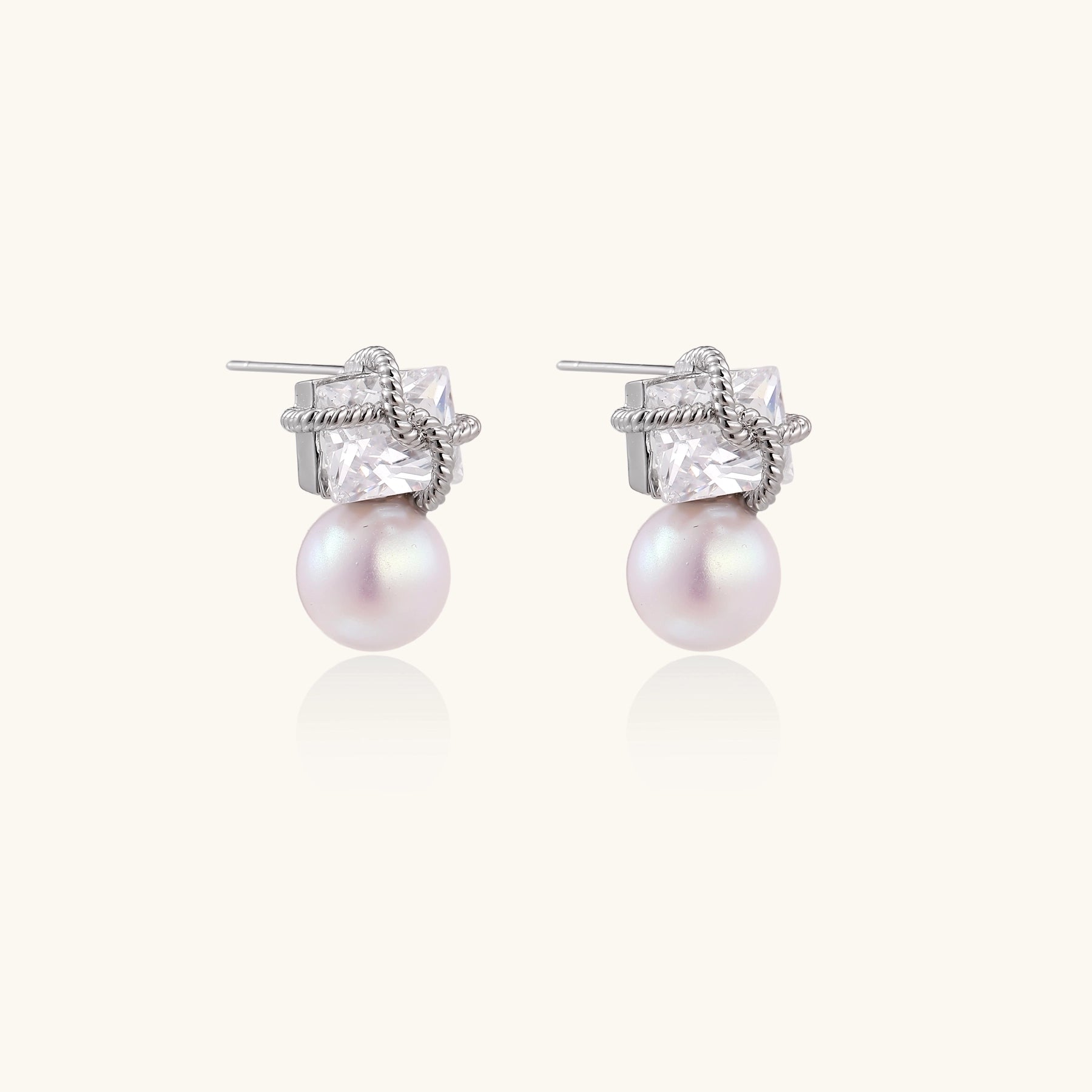 Gold-plated stud earrings with square crystal tops wrapped in twisted wire and freshwater pearl drops on white background