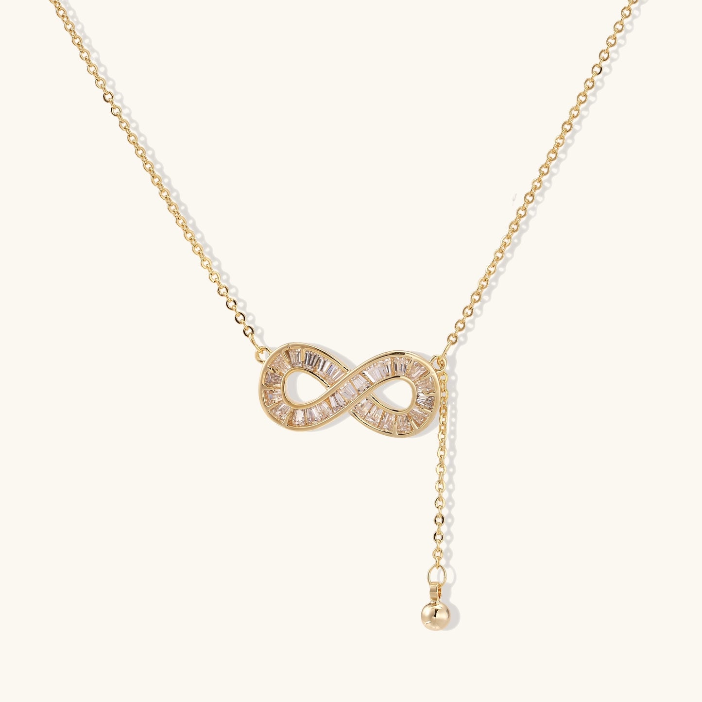 Delicate 14K gold plated infinity pendant with crystal accents on adjustable chain with small ball charm detail.