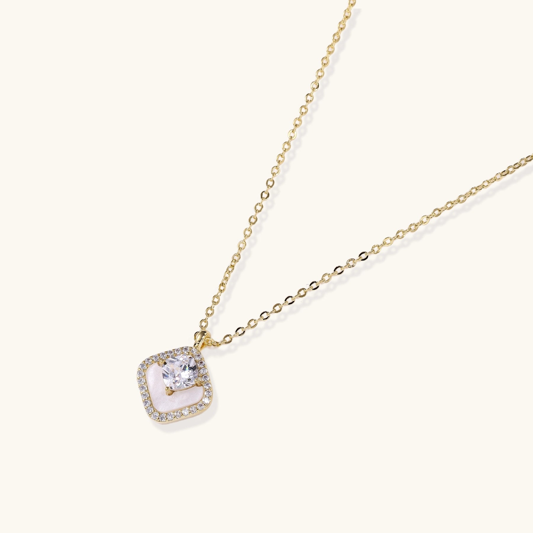 Gold-plated necklace with cushion-shaped pendant featuring a freshwater pearl surrounded by crystal halo on white background.