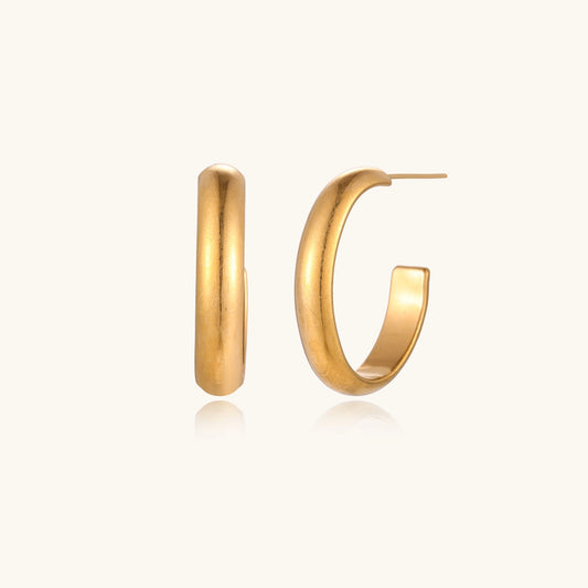 Four pairs of gold-plated stainless steel earrings including hoops and studs displayed on cream background