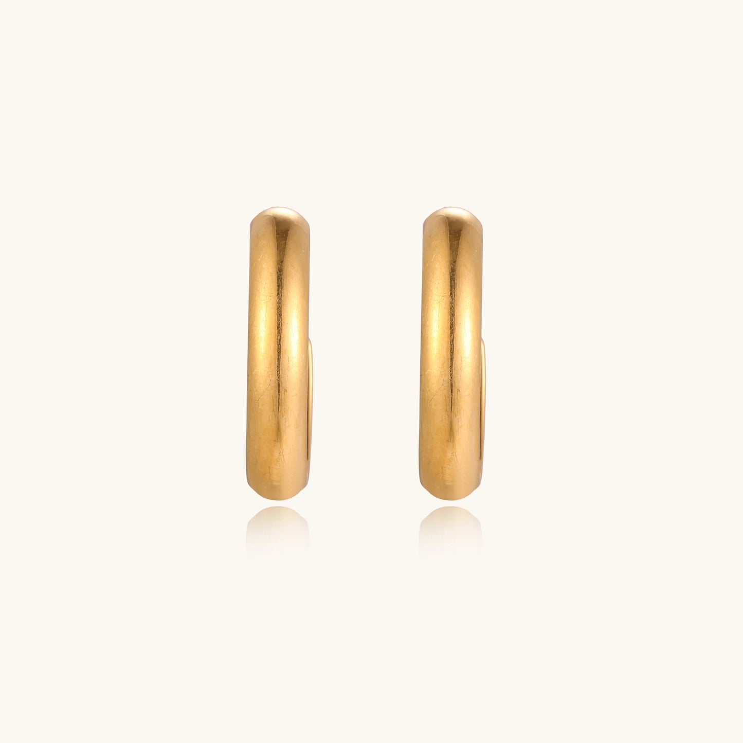 Four pairs of gold-plated stainless steel earrings including hoops and studs displayed on cream background